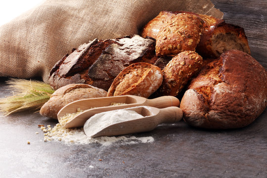 Different kinds of bread and bread rolls on board from above. Kitchen or bakery poster design.