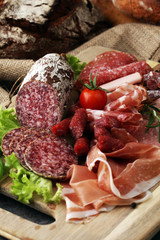 Food tray with delicious salami, pieces of sliced ham, sausage,