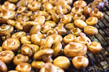 Champignon white mushrooms grilled on grill or BBQ steam and small drops of water. Cooking mushrooms on the grill. Portobello mushrooms marinated and grilling. Grilled vegetables on a grill close up.
