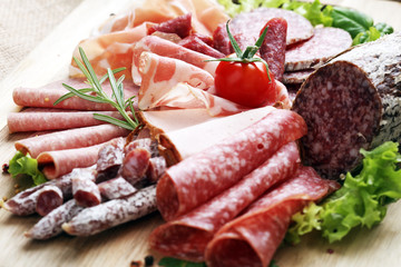 Food tray with delicious salami, pieces of sliced ham, sausage, tomatoes, salad and vegetable - Meat platter with selection