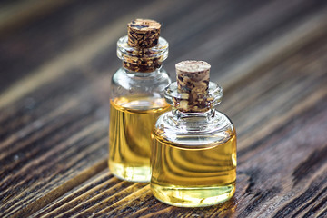 Fototapeta na wymiar Pure organic aroma essential oil in glass bottle isolated on wooden background beauty treatment. Fragrant oil spa concept wellness setting. Selective focus macro front view horizontal. Place for text.
