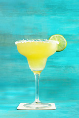 Lemon Margarita cocktail on vibrant turquoise with copyspace
