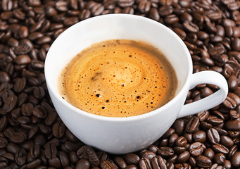 coffee cup on roasted coffee beans as background