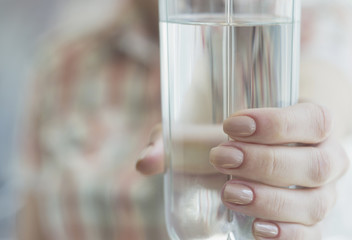 Woman holding a glass of water. Cropped image, selective focus.