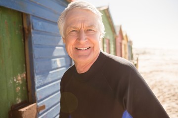 Fototapeta premium Portrait of senior man standing by beach huts