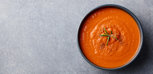 Tomato soup in a black bowl on grey stone background. Top view. Copy space