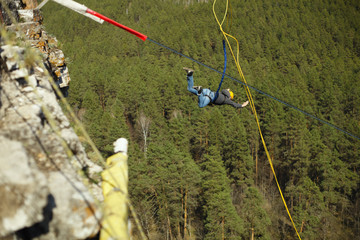 Obraz premium A man jumps into the abyss with a rope from a cliff.