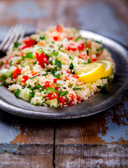 Tabbouleh salad with couscous on the plate.Traditional middle eastern or arab dish.Vegetarian.Parsley,pepper,cucumber,tomato,lemon.Middle eastern meze.Food or Healthy diet concept.Copy space for Text.