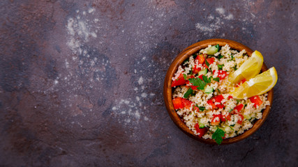 Tabbouleh salad with couscous on the plate.Traditional middle eastern or arab dish.Vegetarian.Parsley,pepper,cucumber,tomato,lemon.Middle eastern meze.Food or Healthy diet concept.Copy space for Text.
