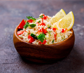 Tabbouleh salad with couscous on the plate.Traditional middle eastern or arab dish.Vegetarian.Parsley,pepper,cucumber,tomato,lemon.Middle eastern meze.Food or Healthy diet concept.Copy space for Text.