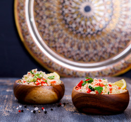 Tabbouleh salad with couscous on the plate.Traditional middle eastern or arab dish.Vegetarian.Parsley,pepper,cucumber,tomato,lemon.Middle eastern meze.Food or Healthy diet concept.Copy space for Text.