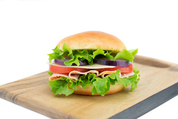 Fresh sandwich with vegetables and ham on the wooden board isolated on white background