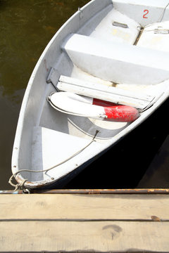 boat white at the shore pier, wooden on the dark river water tied strong rope and with lifeline on Board
