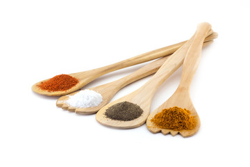 Spices on three wooden spoons isolated on white background
