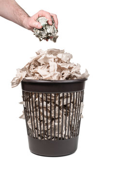 Man hand throws crumpled dollars into a trash can with paper isolated on a white background