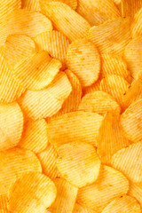 Background of golden wavy corrugated chips large slices with seasoning throughout the frame, appetizing food background