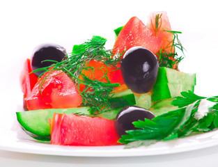Greek salad is delicious, juicy, vegetarian salt, oil, shiny on a white plate isolated on white background