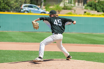 Mens' baseball pitcher winding up to throw the curveball.  
