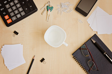 Top view office desk with notepads, phone, paper for notes, calculator, glasses and  cup for coffee
