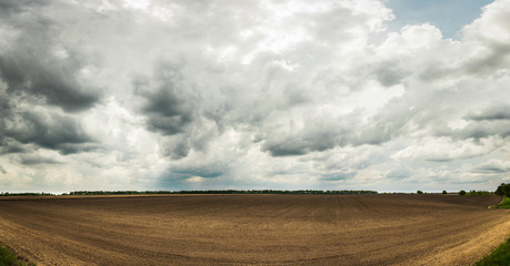 Beautiful Ukrainian landscape with a spring field after planting and dramatic sky.