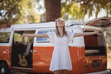 Woman with arms outstretched standing by van