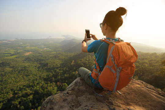 successful woman hiker taking photo with cellphone hiking on mountain peak