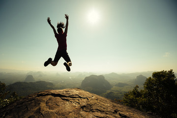 freedom woman hiker jumping on sunrise mountain top