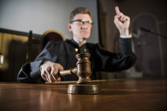 a judge with a hammer in his hand in the court room