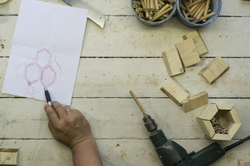 Close Up of a carpenter hands, he is building an insect shelter for wild bees on a workbench