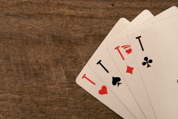 Four playing card aces on a wooden table.