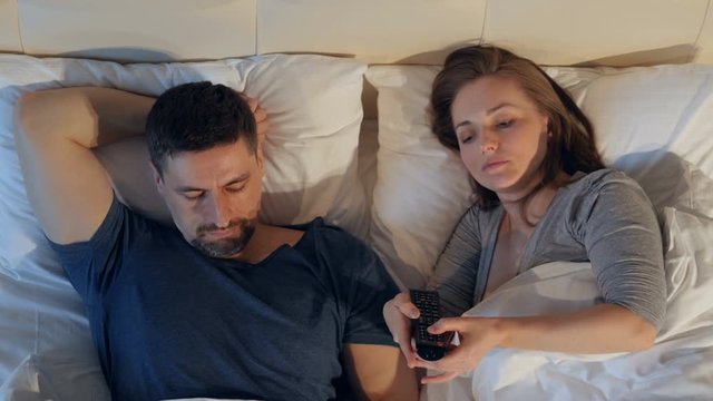 The couple quarreling sharing remote control, watching the TV.