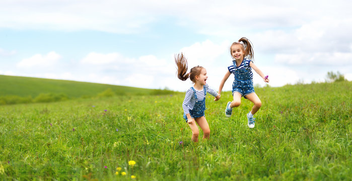 happy children twins sisters jumping and laughing  in summer