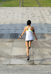 young fitness woman jumping rope on city
