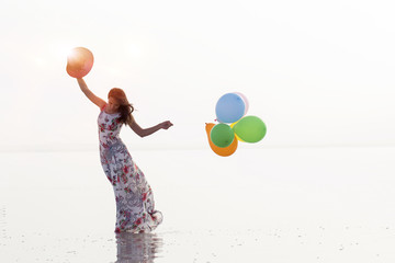 Woman holding colorful balloon, walking on the beach with blue sky. The idea of a woman holding a beach balloon.Vintage background photo