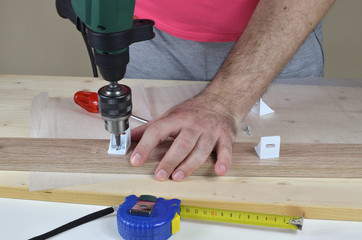 Man holding an electric screwdriver and installing elements of a cabinet