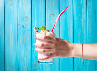 Woman hand and Homemade milkshake with caramel on blue wooden table
