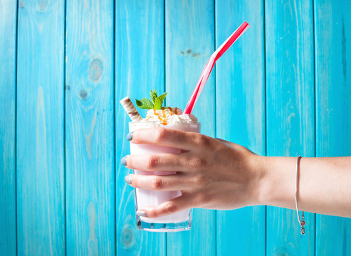 Woman hand and Homemade milkshake with caramel on blue wooden table