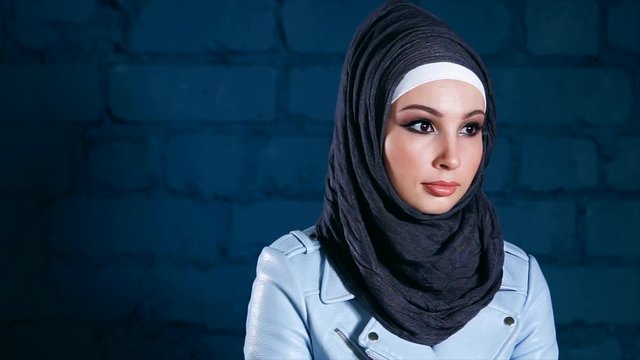 Indoor portrait of a beautiful Middle Eastern girl wearing black hijab. Young Muslim woman shifting her gaze and looking to the camera