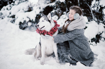 Fototapeta na wymiar beautiful young girl in winter forest with Siberian Husky. Symbol of new year 2018