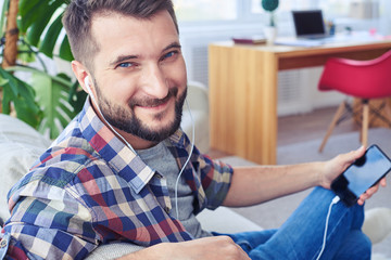 Fototapeta premium Guy with beautiful blue eyes listening to music with headphones and smiling