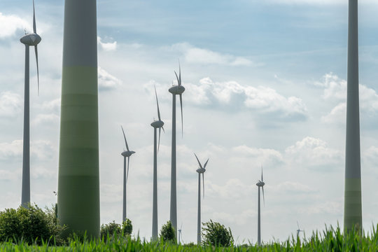 Windkraftanlagen auf grüner Wiese vor blauem Himmel mit Wolken