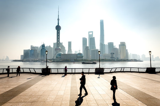 Les buildings de Shanghai en contre jour avec des promeneurs en ombre chinoise sur un parvis