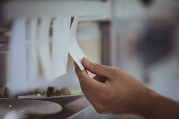 Close-up of chef holding an order list in the commercial kitchen