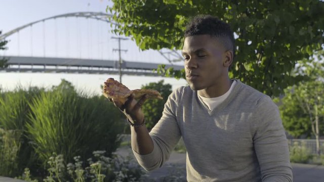 Man Sits In An Urban Park And Takes First Bite Of Pizza, He Really Savors It