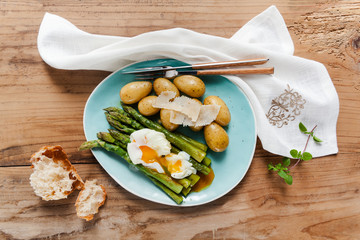 Light spring lunch on the plate. Fried asparagus, fresh potatoes and poached egg with parmesan cheese. healthy food.
