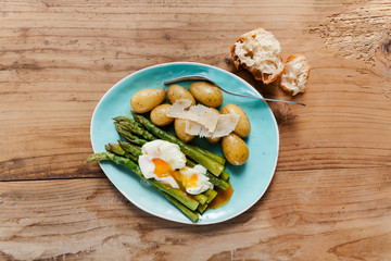 Light spring lunch on the plate. Fried asparagus, fresh potatoes and poached egg with parmesan cheese. healthy food.