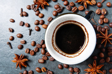 Coffee cup with coffee beans on stone table background with star anise.