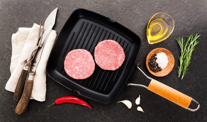 raw Chicken turkey burgers on grill pan with cutting Cutlery for slicing and spices