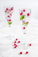 Ice cubes with berries and mint in glasses for summer drink white background