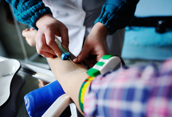Doctor making blood analysis young girl patient. Blood sampling from a vein on the background of the clinic